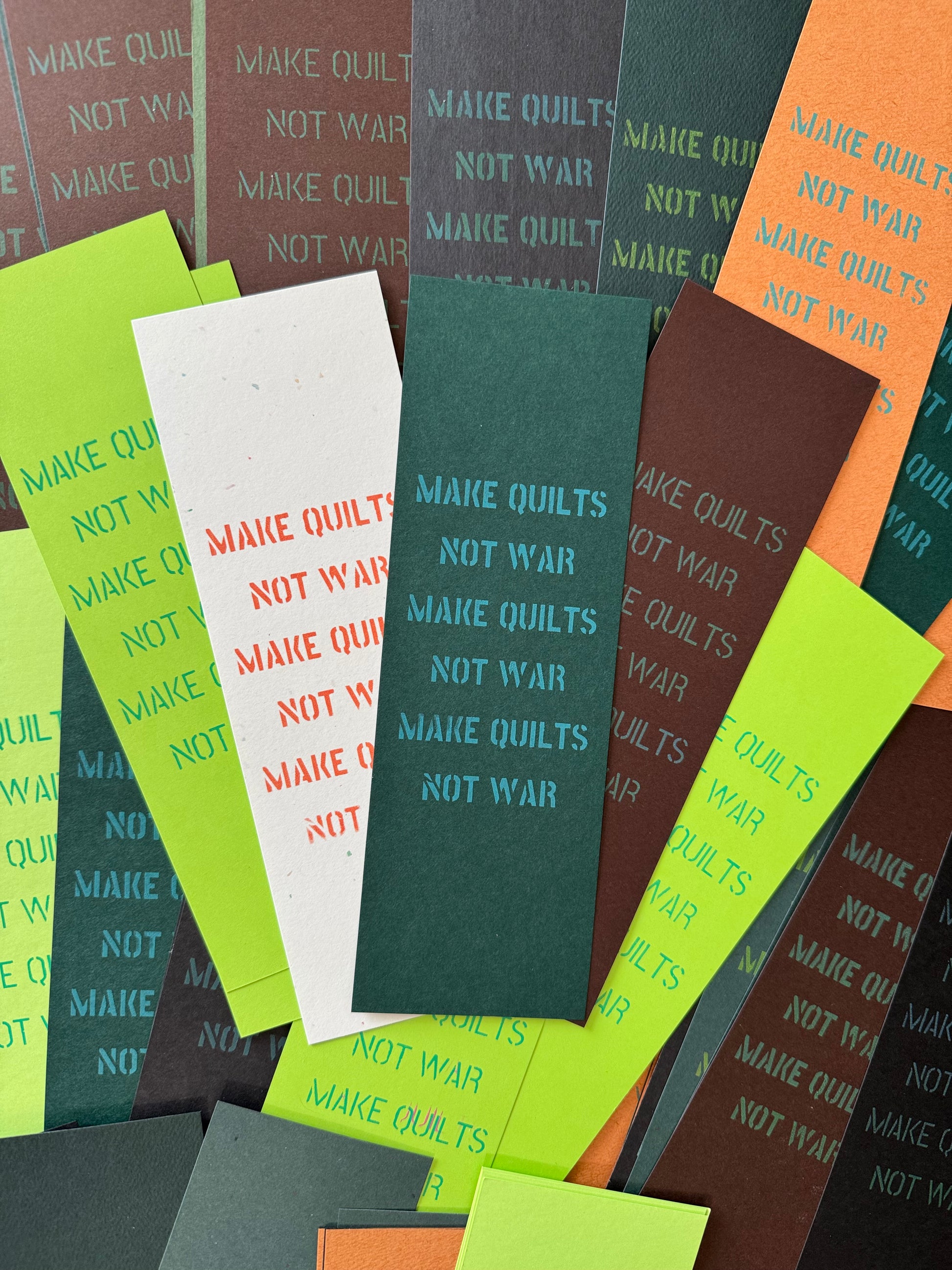 Colorful bookmarks with 'Make Quilts Not War' unique screen printed text.